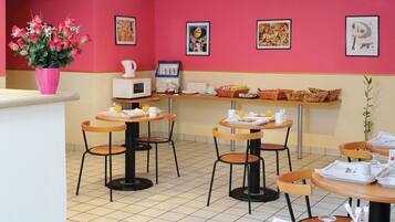 A dining area with tables and chairs, a coffee machine, and a vase of flowers.