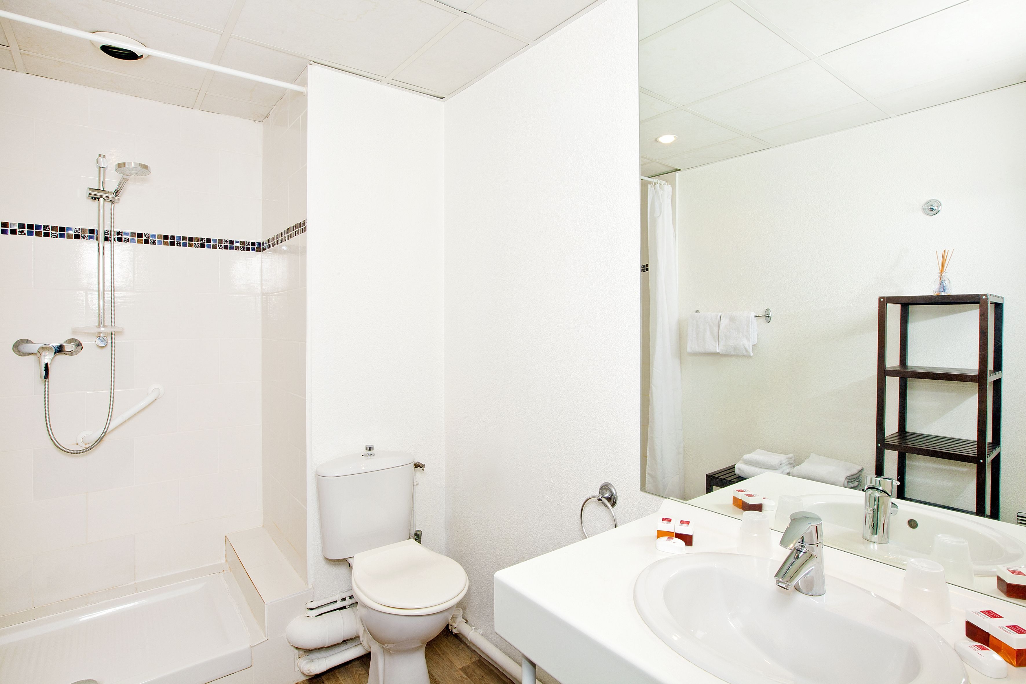 A modern bathroom with a bathtub, toilet, and a large mirror above the sink.