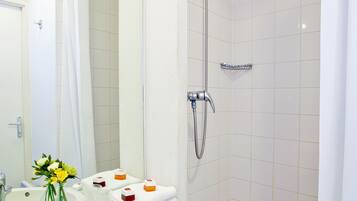 A bathroom with a sink, mirror, shower, and a towel rack.