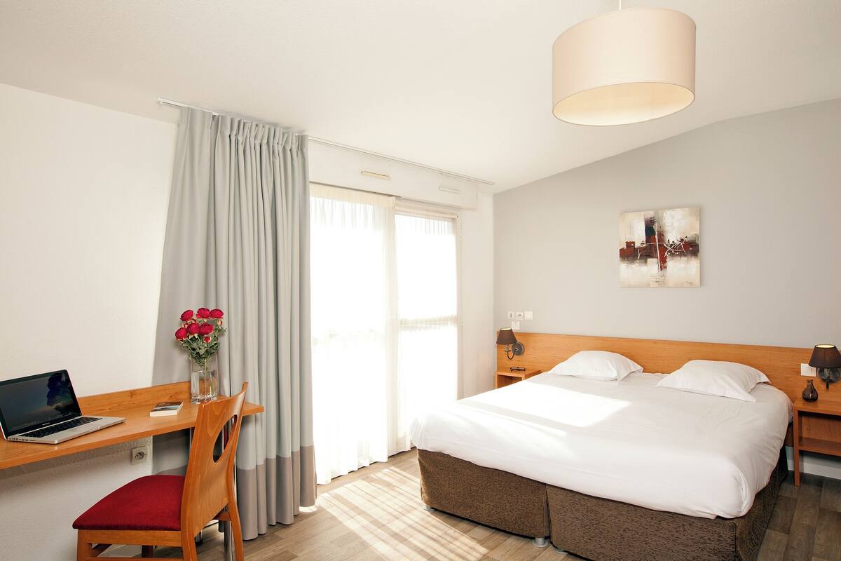 Une chambre d’hôtel équipée d’un lit, d’un bureau, d’une chaise et d’une lampe.