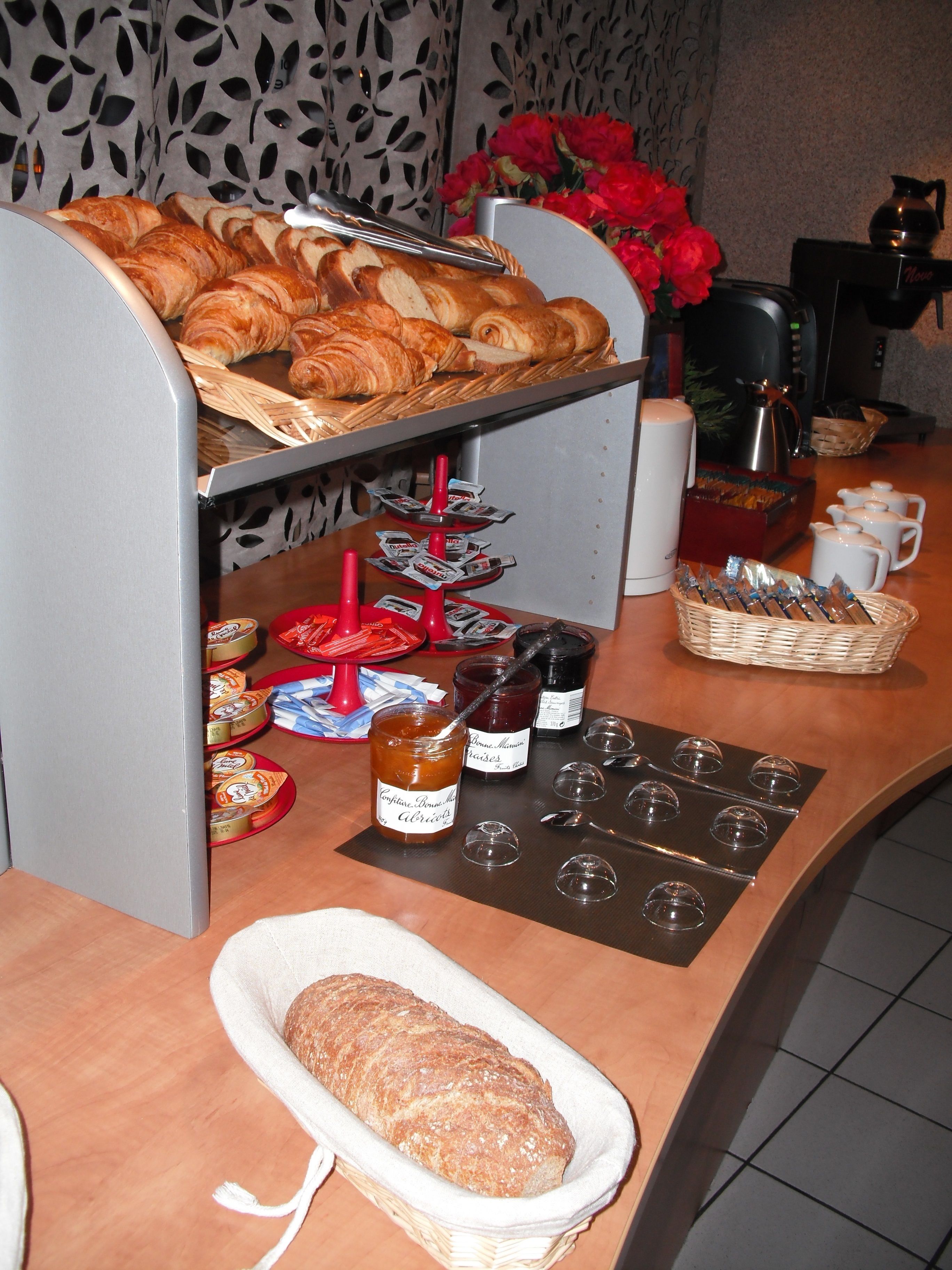 A breakfast buffet with pastries, jams, and bread.