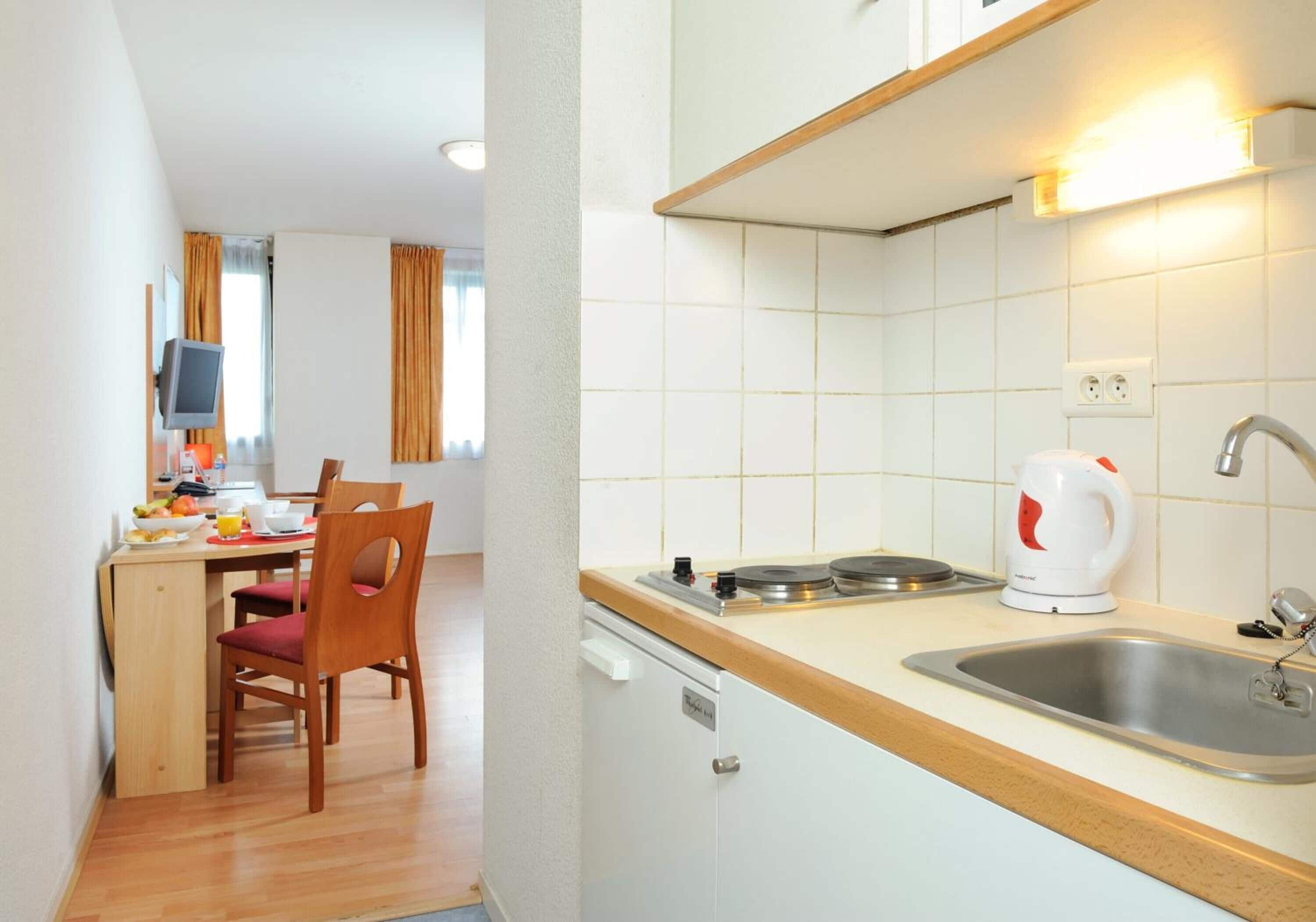 A compact kitchen with a wooden countertop, a sink, and a white kettle.