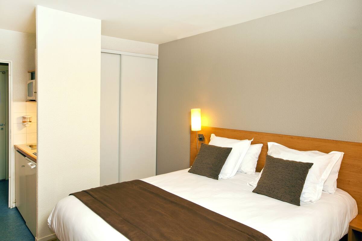 Een hotelkamer met een bed, een bedlamp en een houten hoofdeinde.
