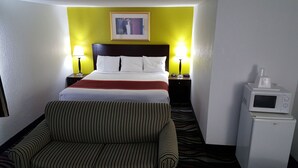 A hotel room with a bed, two bedside lamps, a framed picture on the wall, a microwave, and a striped chair. - Horizon Inn Motel (Lincoln)