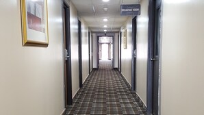 A hotel hallway with a checkered carpet, doors on both sides, and a sign indicating a breakfast room. - Horizon Inn Motel (Lincoln)