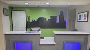 A reception desk with a cityscape mural, a white door, and a framed sign on the wall. - Horizon Inn Motel (Lincoln)