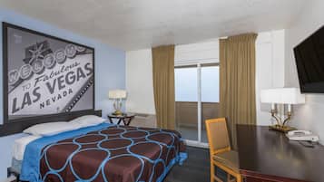 A hotel room with a bed, a desk, a chair, a lamp, a telephone, and a window with curtains.
