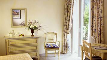 Une chambre à coucher avec un lit, une commode, une chaise, une table et une fenêtre avec des rideaux.