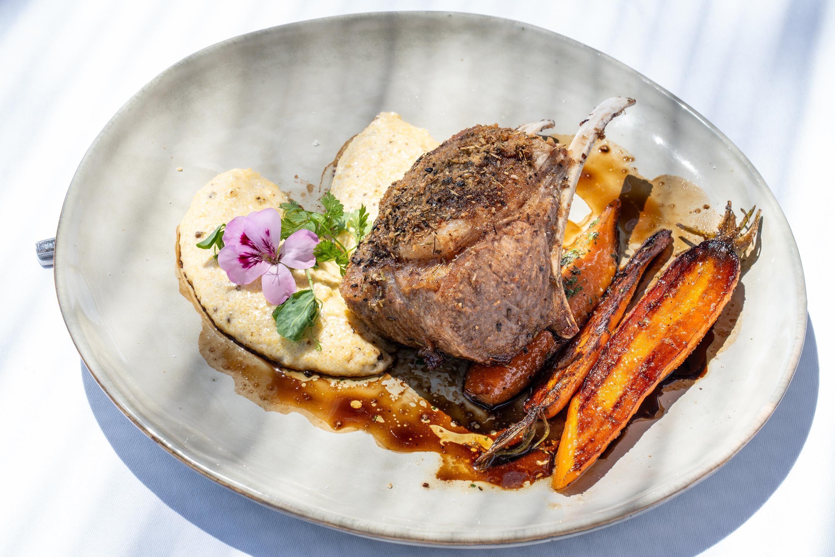 Ein Teller mit gebratenem Fleisch, Kartoffelpüree und geröstetem Gemüse.