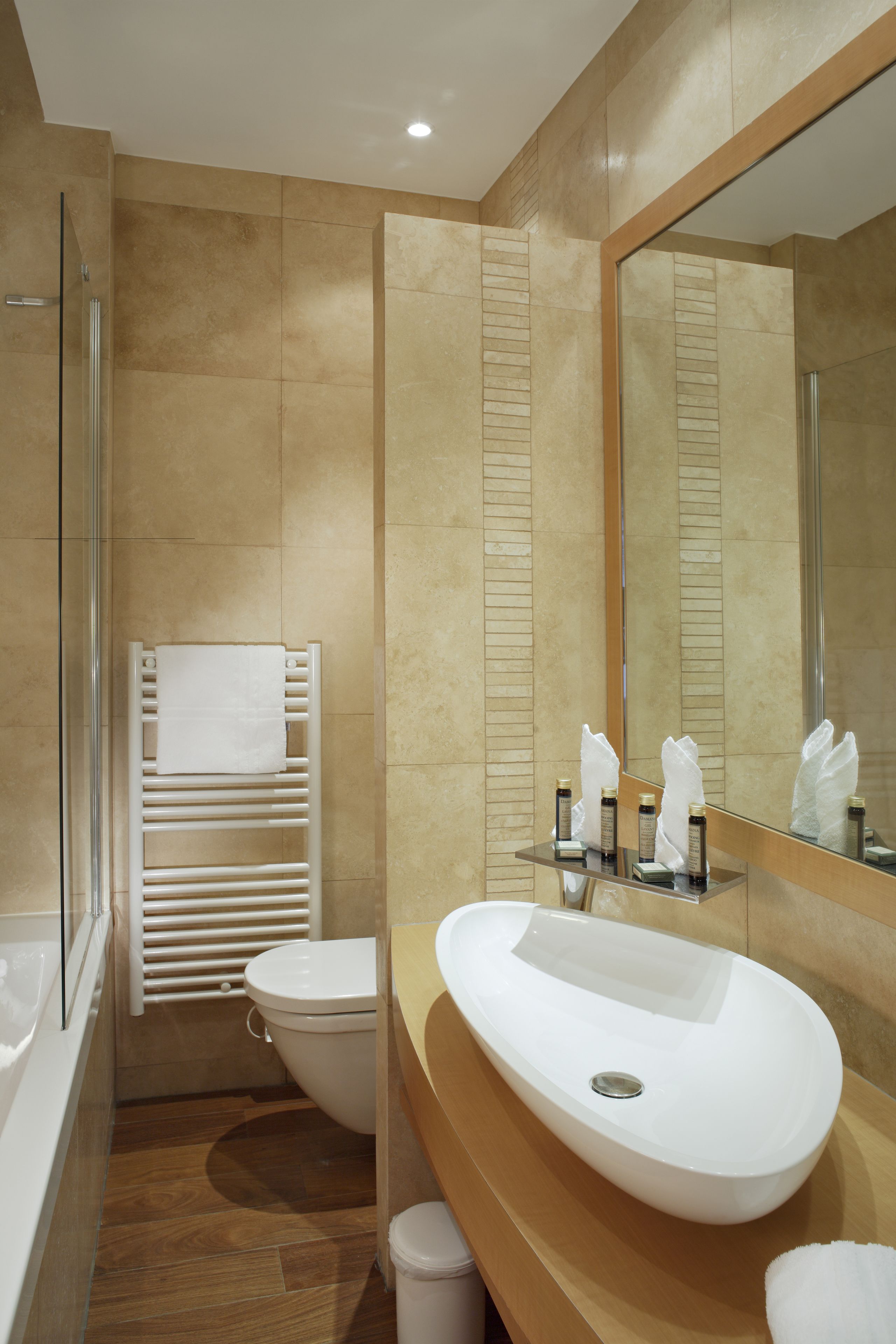 Une salle de bain moderne avec un grand miroir, un lavabo blanc et une douche à parois de verre.