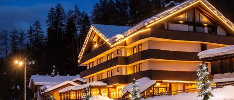 A multi-story hotel with a snow-covered roof and illuminated exterior.