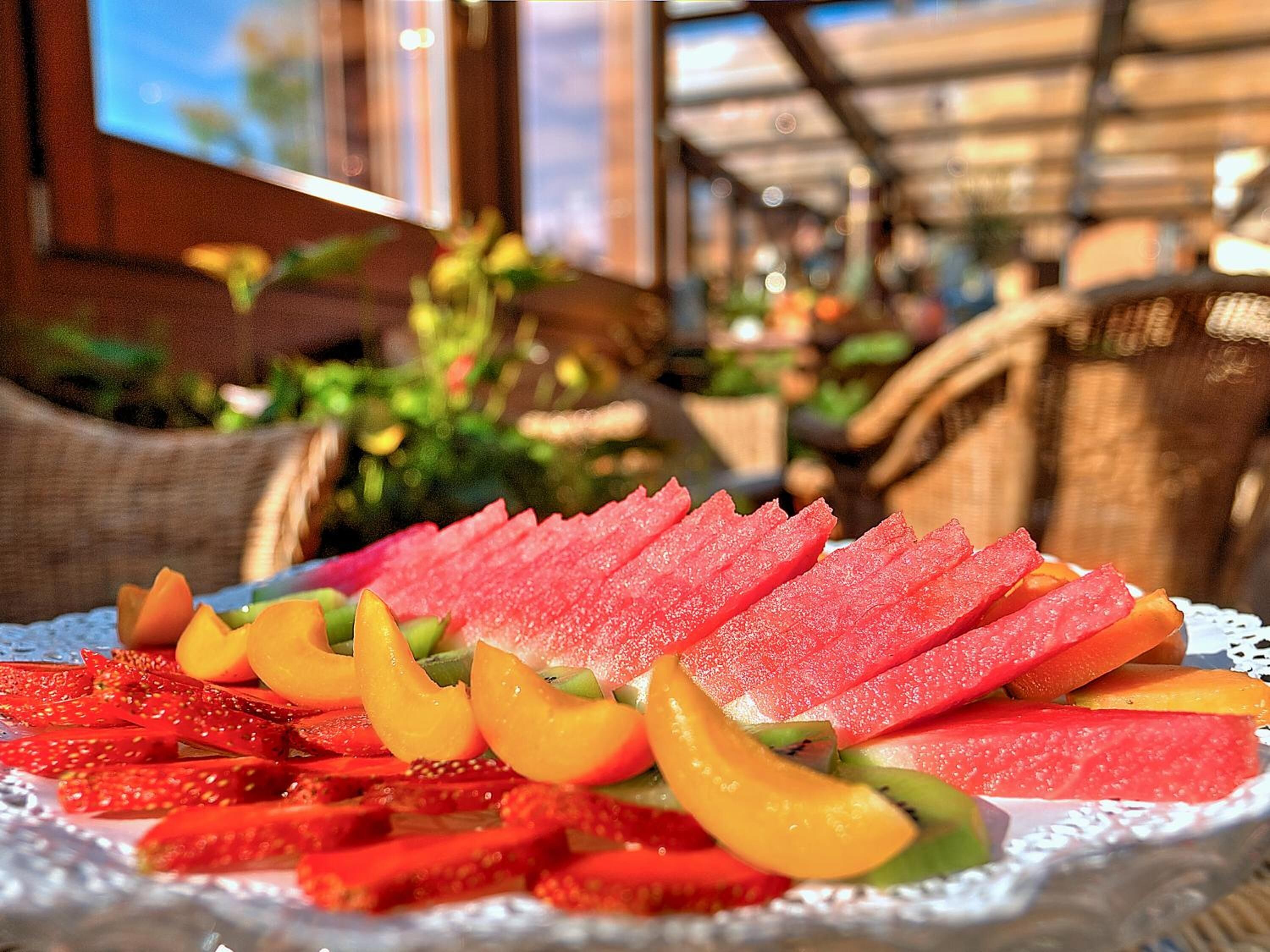 A fruit platter on a table with a wicker chair and a wicker basket in the background.