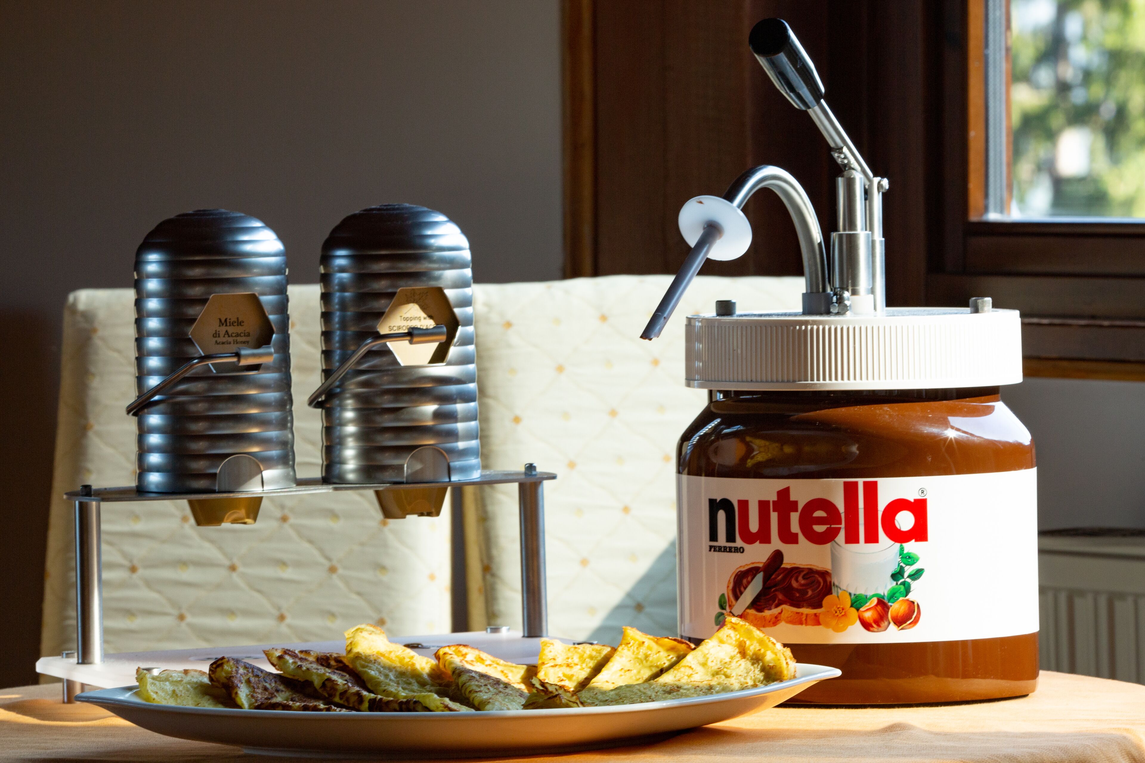 Une assiette de sandwichs grillés, accompagnée d’un pot de Nutella, posée sur une table.