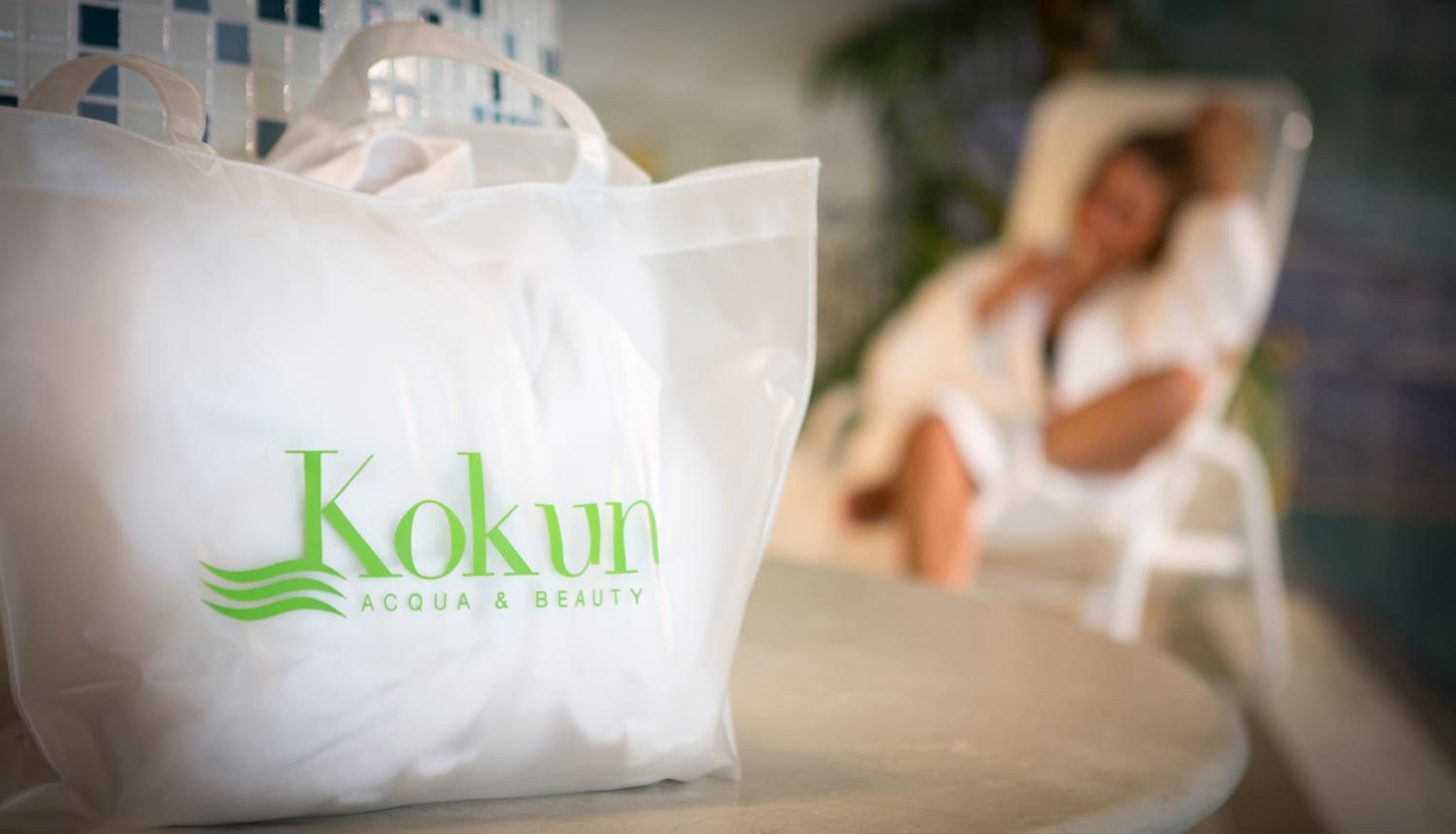 A white Kokun bag with the text "ACQUA & BEAUTY" on a table.