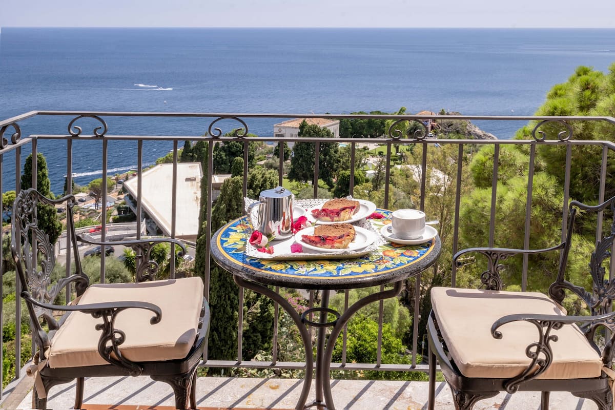 Un balcon avec une table dressée pour le thé, offrant une vue sur la côte.