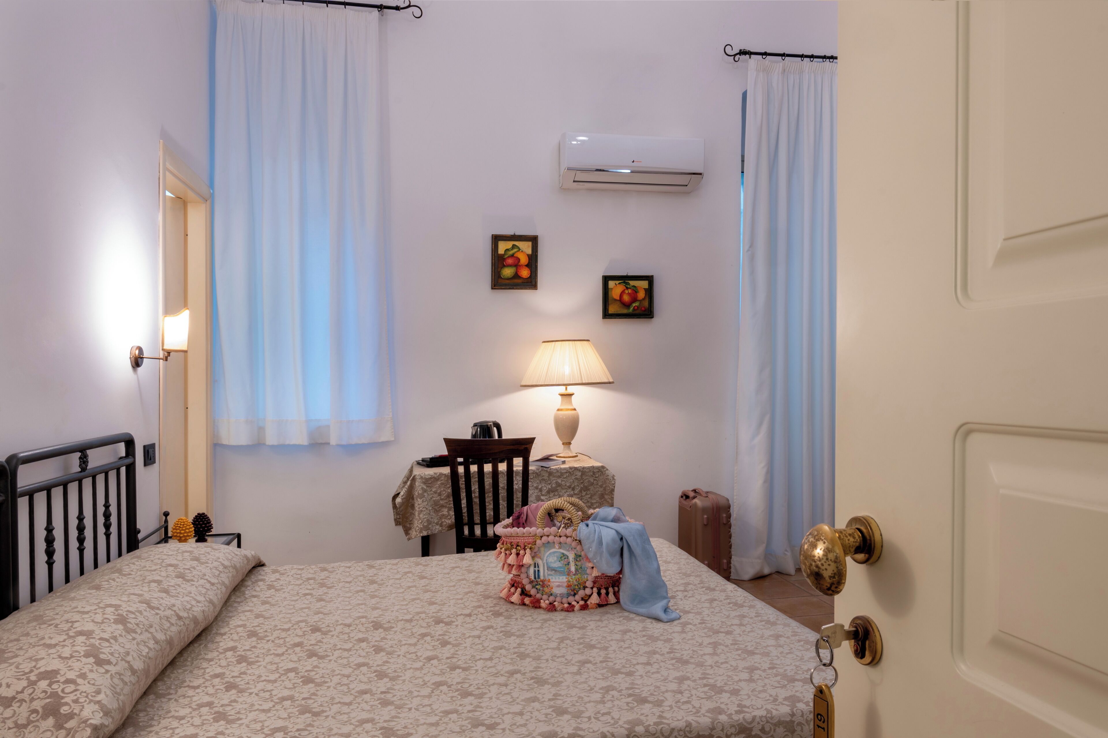Een slaapkamer met een bed, nachtkastje, lamp en een airconditioning op de muur.