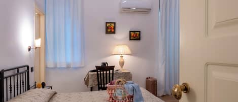 A bedroom with a bed, a bedside table, a lamp, and an air conditioning unit on the wall.