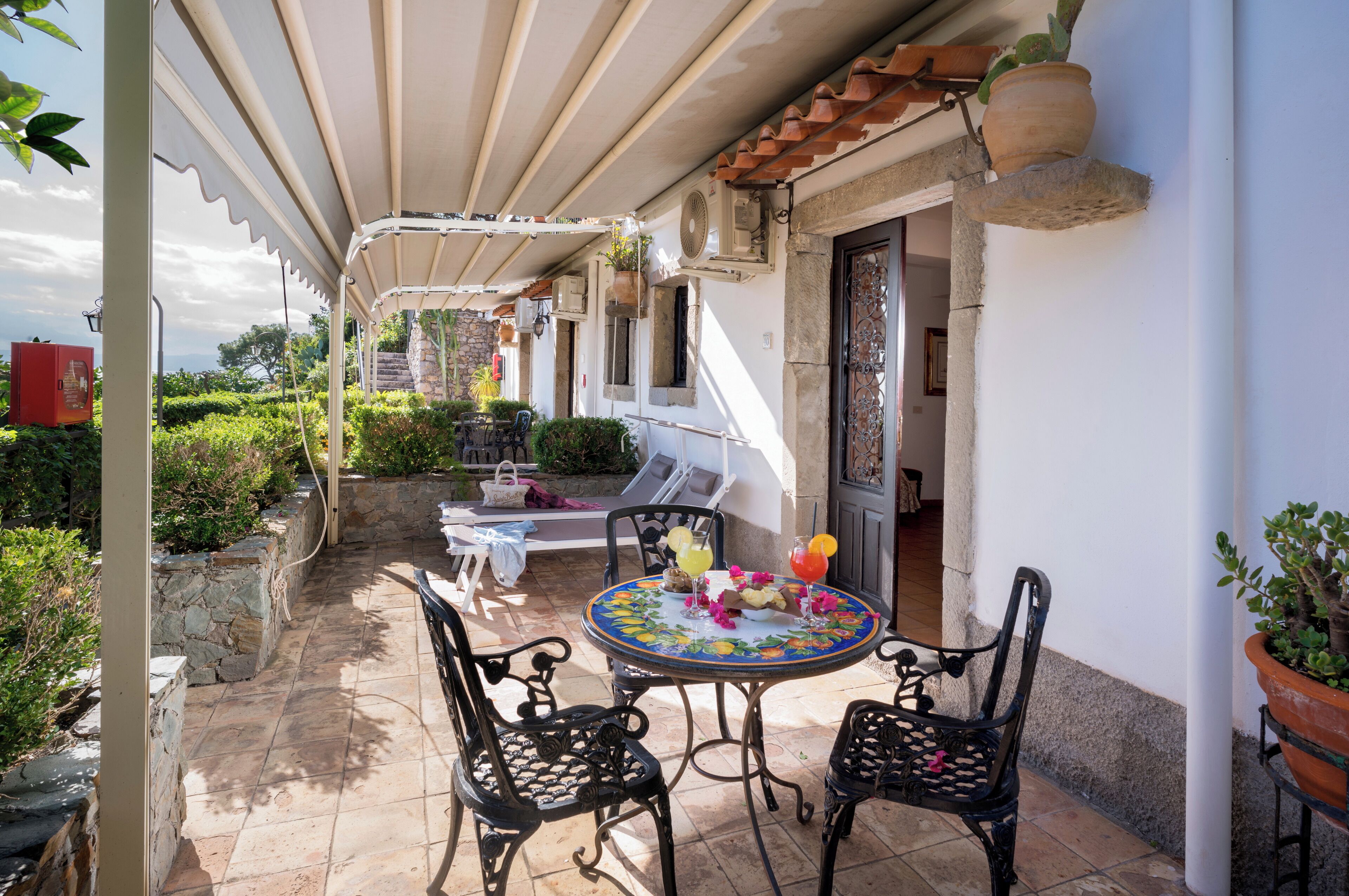 An outdoor patio with a round table, two chairs, and a covered seating area.