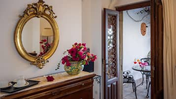 Une pièce comprenant une commode en bois, un miroir et un vase de fleurs.