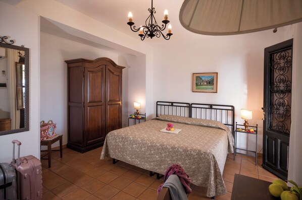 A bedroom with a large bed, a wooden wardrobe, a chandelier, and a door with intricate metalwork.