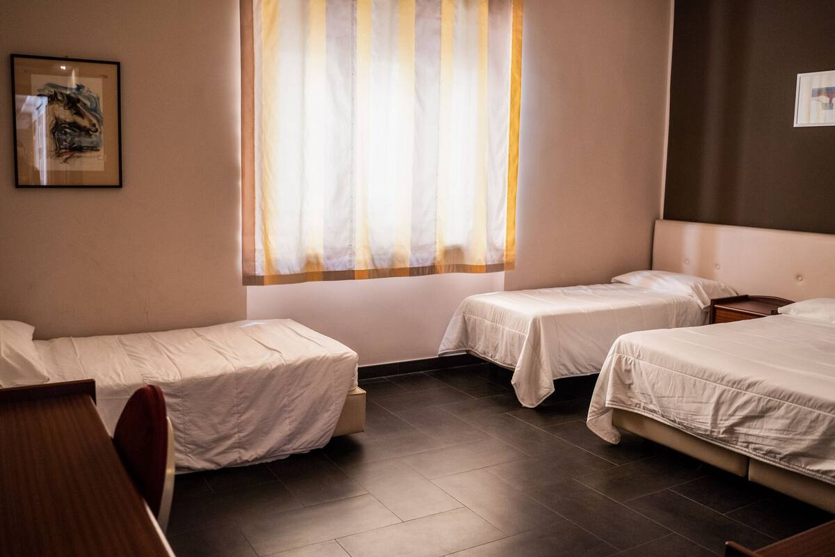 A hotel room with two single beds, a desk, and a chair.