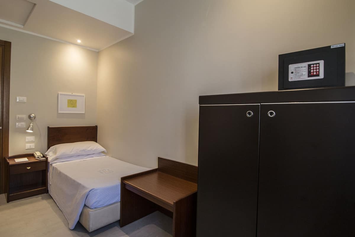 A hotel room with a bed, bedside table, lamp, and a large wardrobe.