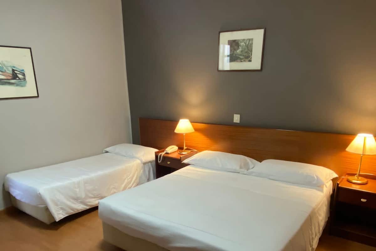 A hotel room with two beds, a wooden headboard, bedside lamps, and a framed picture on the wall.