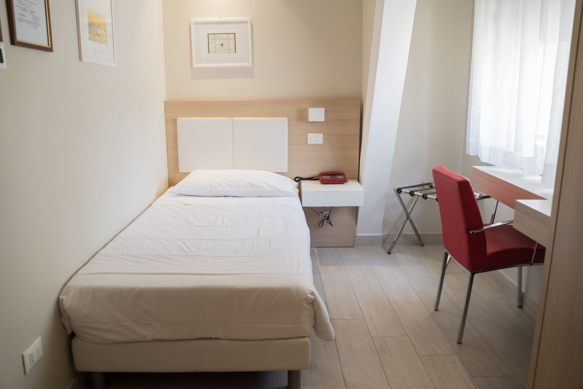 Une petite chambre à coucher, bien rangée, avec un lit, un bureau et une chaise.