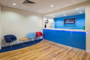 Un área de recepción con un mostrador azul, un reloj y tres sillas.