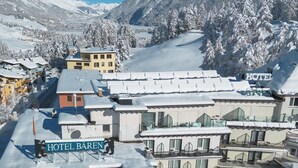 A snow-covered hotel complex with multiple buildings, including a visible sign for 'HOTEL BAREN.' - Hotel Bären (St. Moritz)