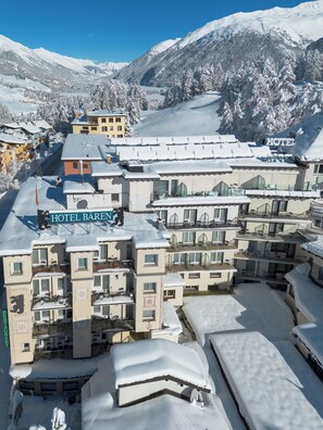 A snow-covered hotel complex with multiple buildings, including a visible sign for 'HOTEL BAREN.' - Hotel Bären (St. Moritz)