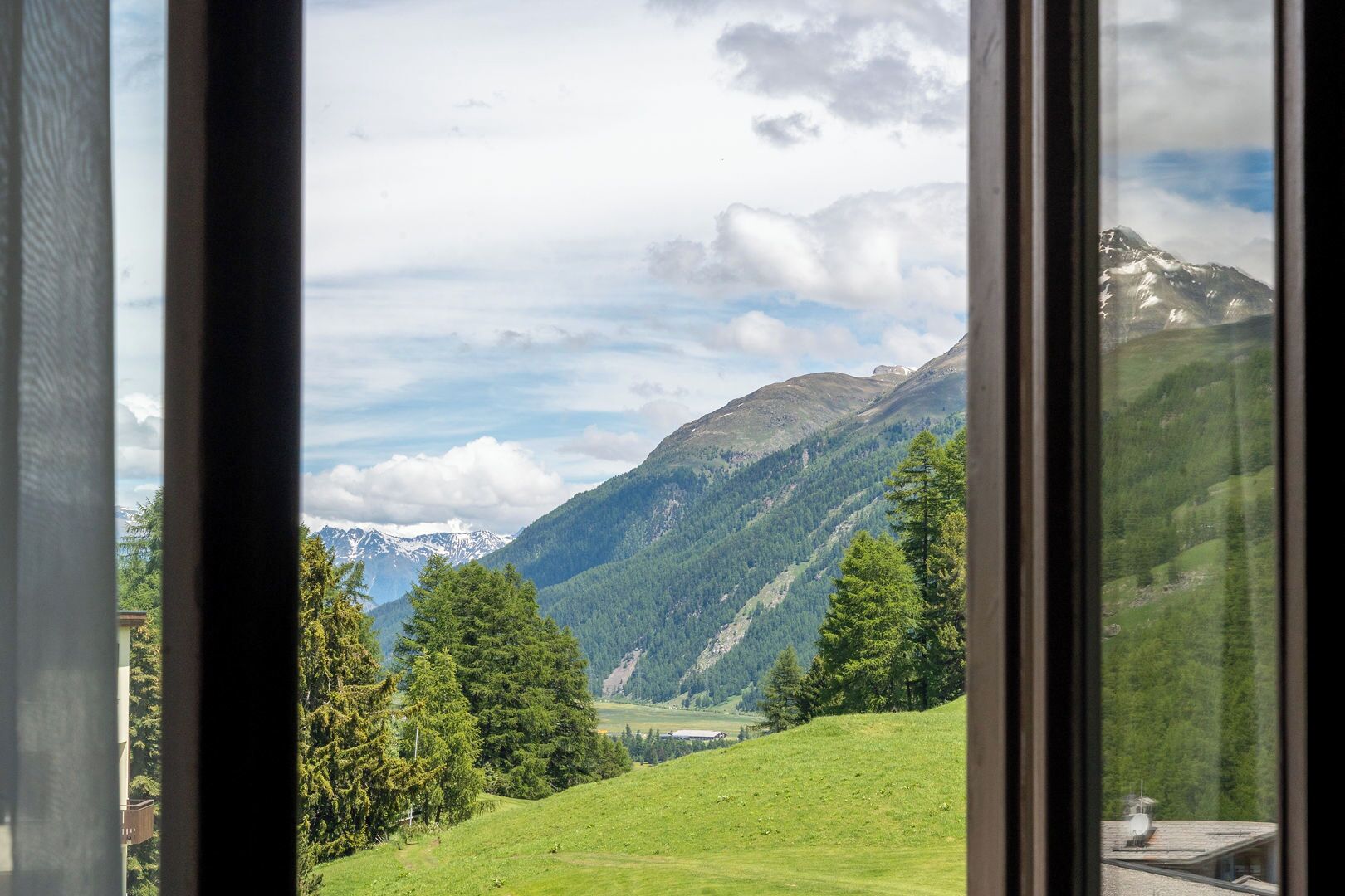 A view through a window of a mountainous landscape with a clear sky.