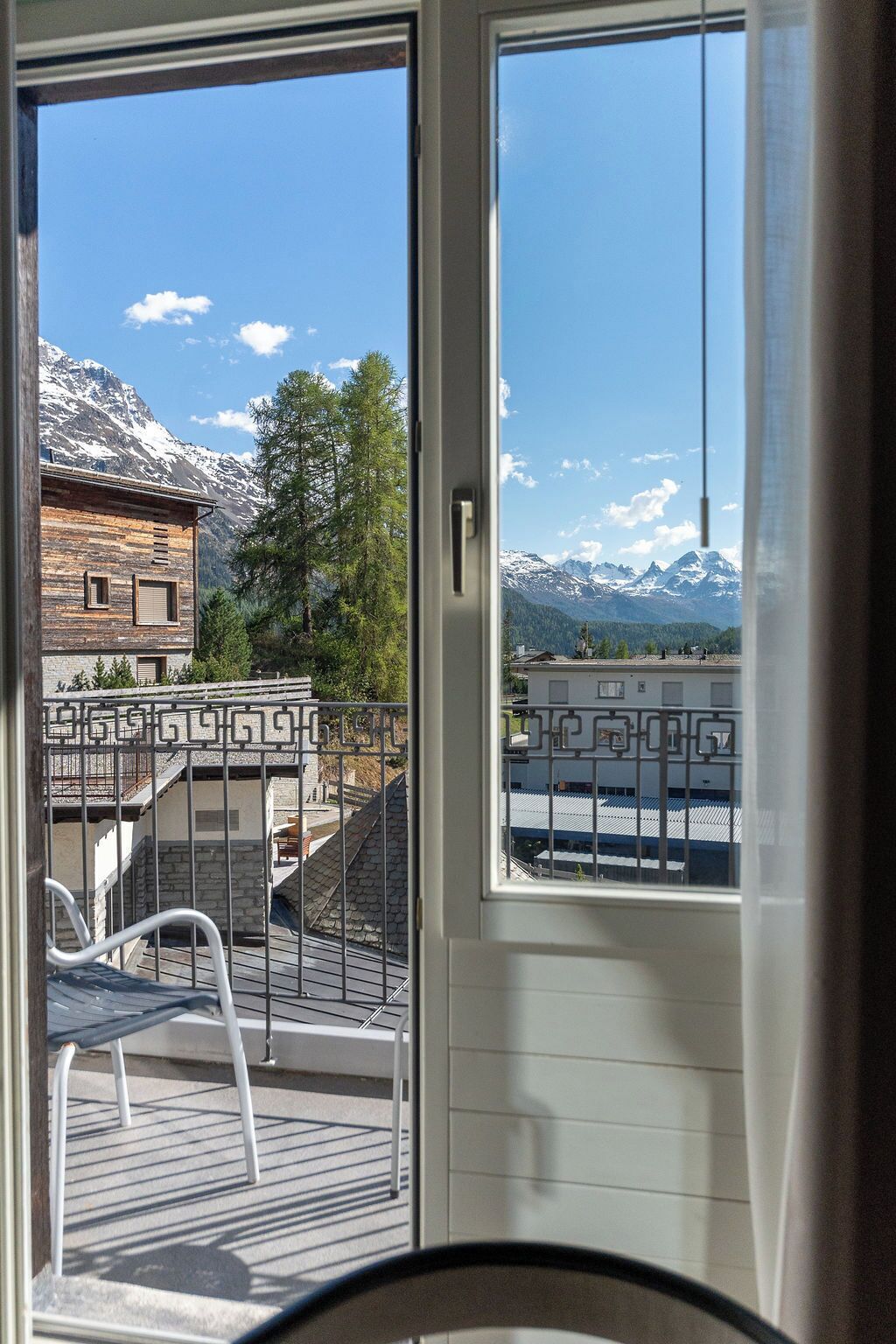 A balcony with a view of a mountain range and a building with a wooden facade.