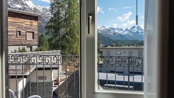 A balcony with a view of a mountain range and a building with a wooden facade.