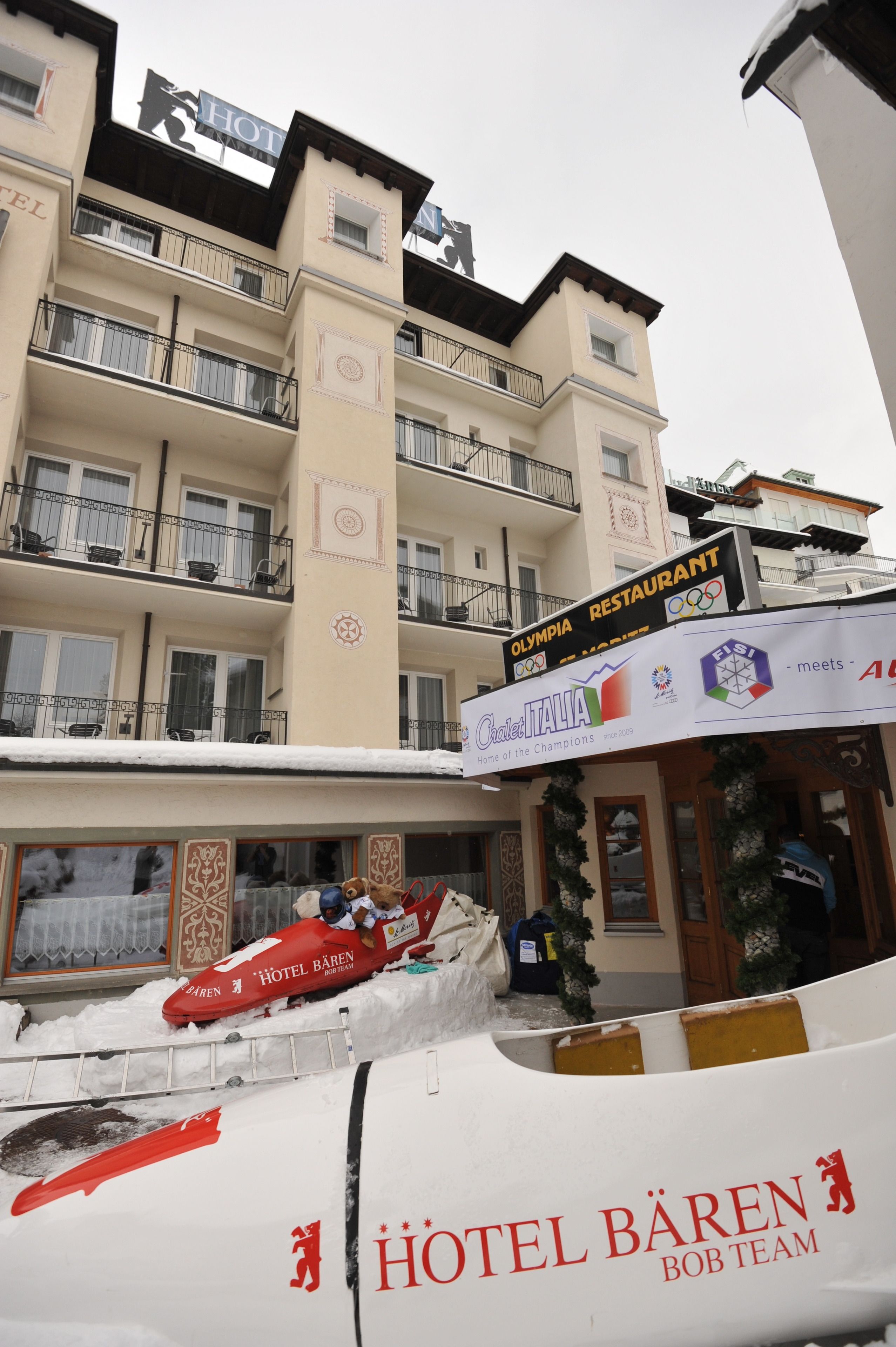 Un hotel con varios balcones, un letrero de restaurante y un cartel anunciando los Juegos Olímpicos.