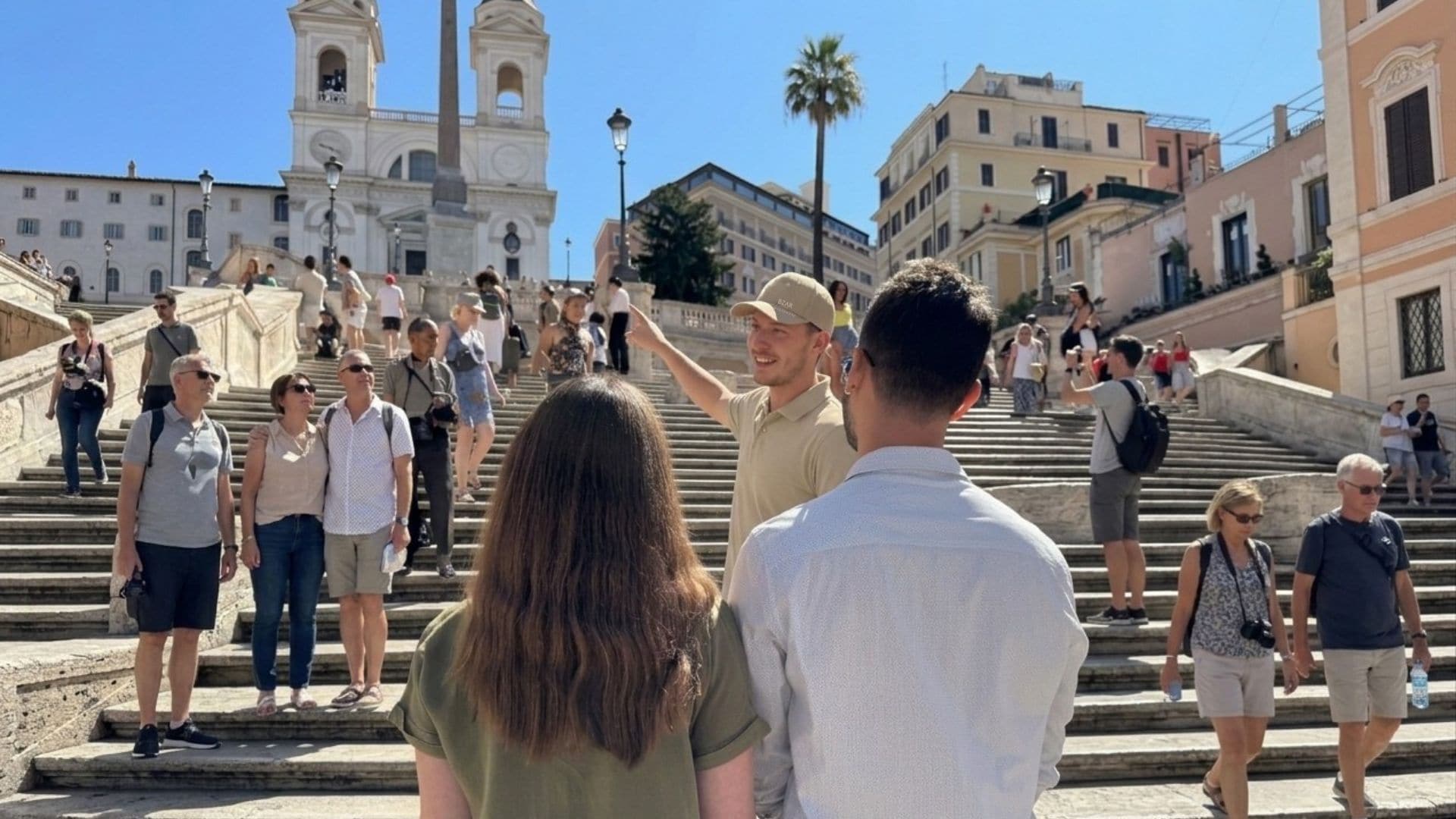 A group of people ascending a set of stone steps towards a historic building with a bell tower.