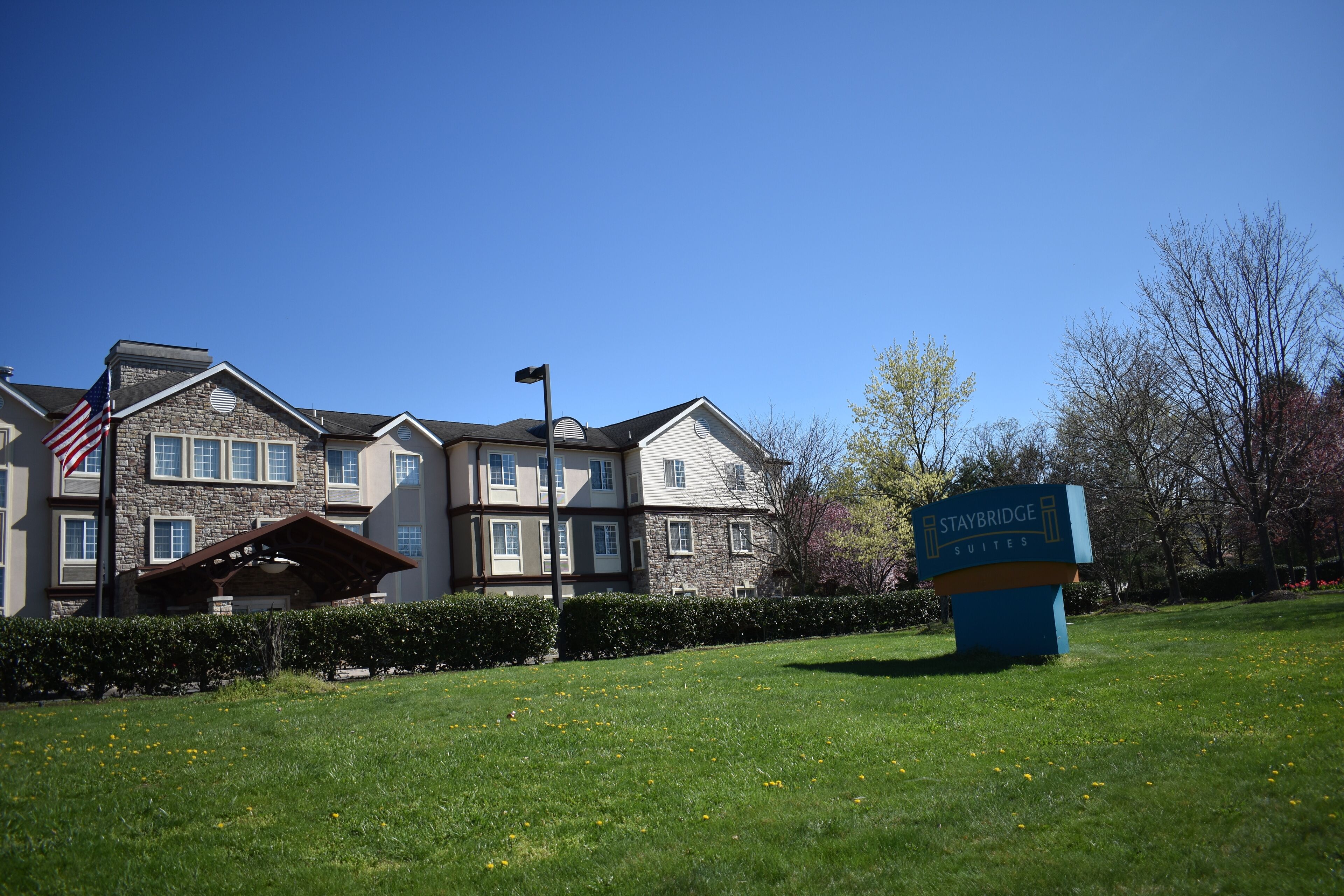 A hotel with a stone facade, a covered entrance, and a sign indicating Staybridge Suites.