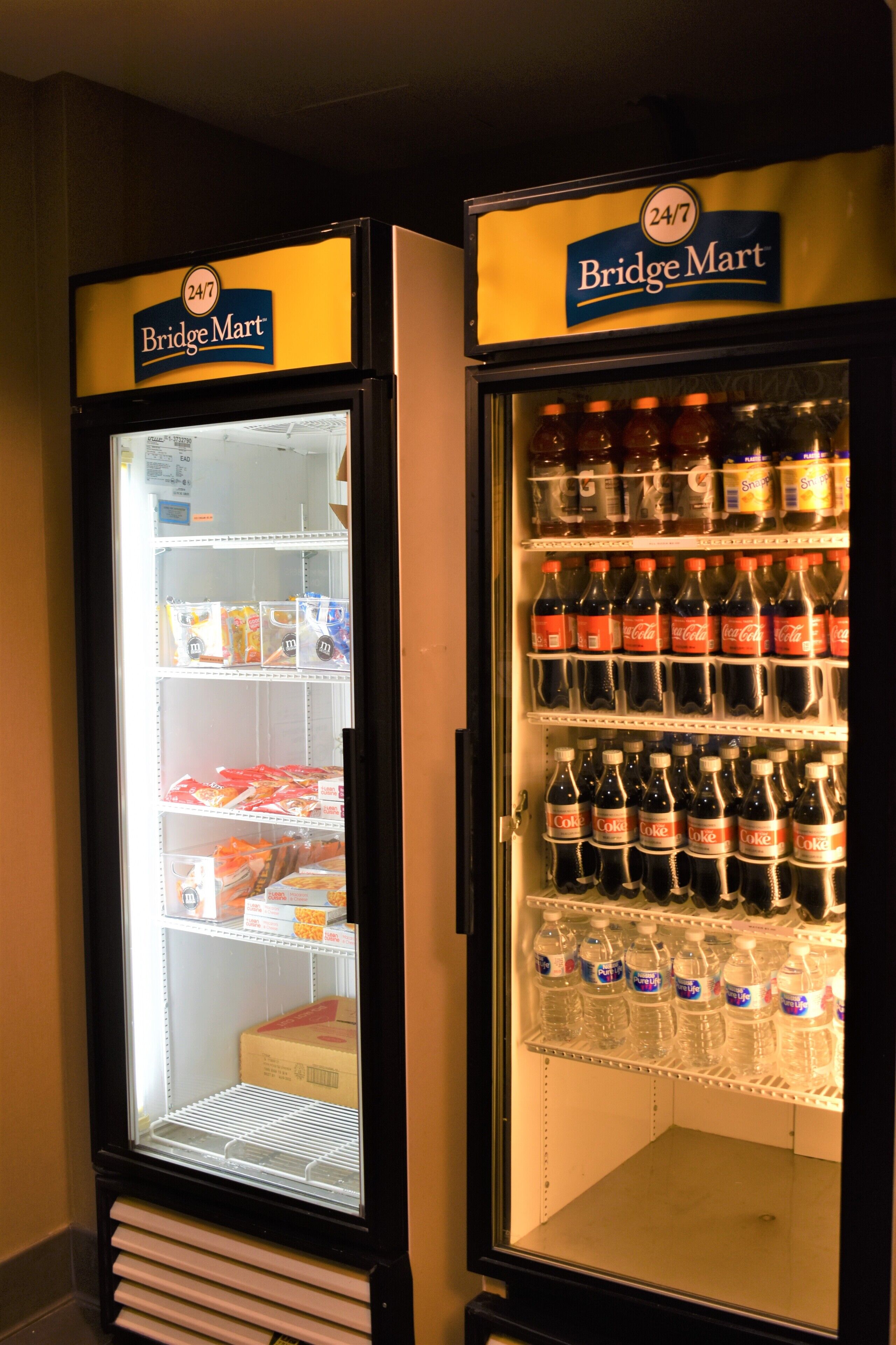 Dos refrigeradores BridgeMart, uno con bebidas y otro con aperitivos.