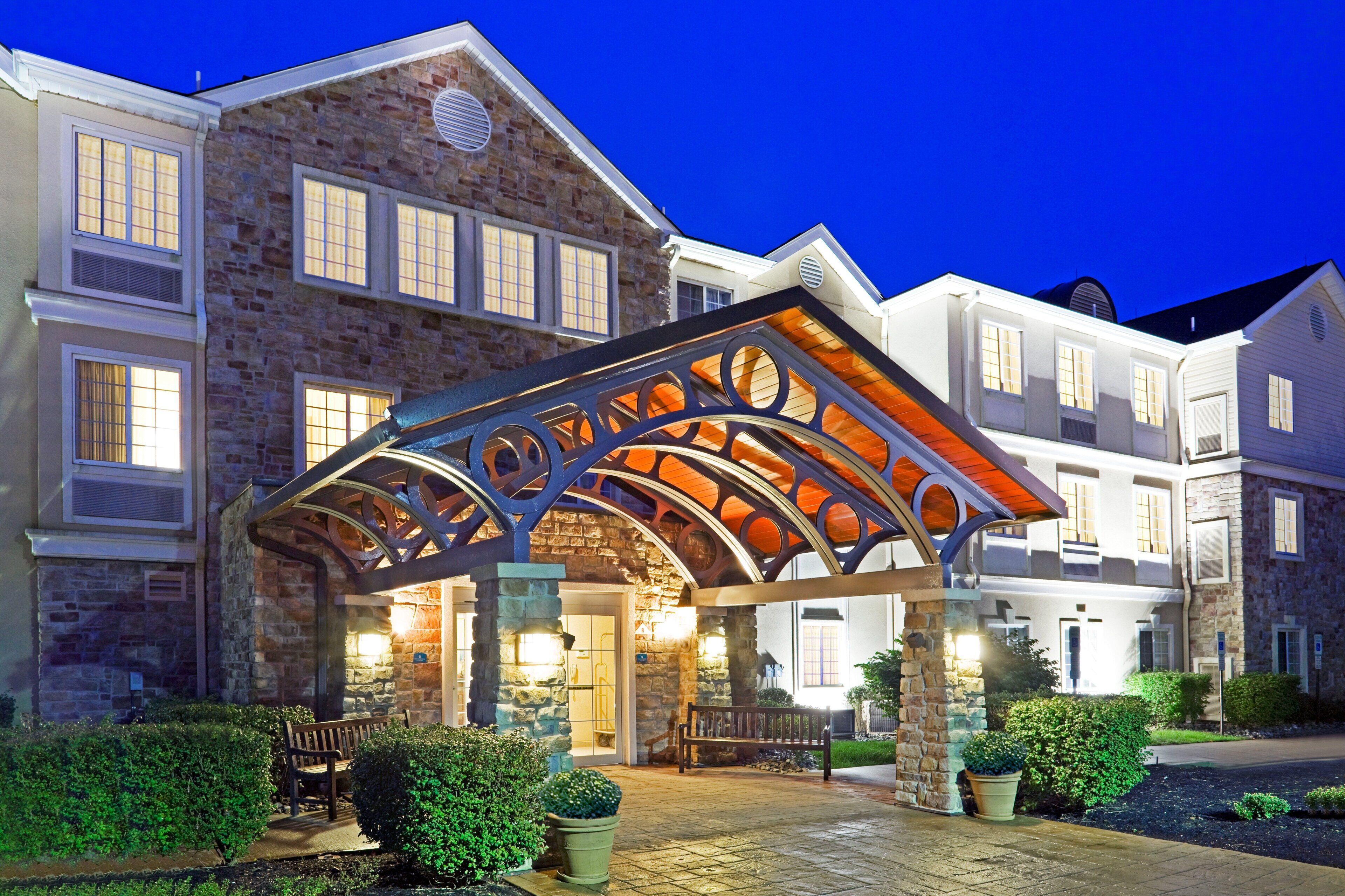 A hotel entrance with a stone facade, multiple windows, and a covered patio area.