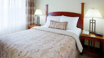 A hotel room with a large bed, two bedside tables, a telephone, and a lamp on each side.