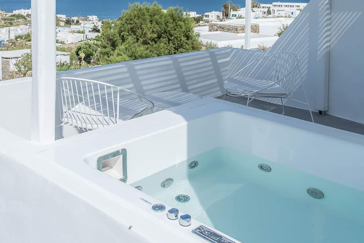 Una piscina infinita blanca con vistas despejadas al mar y edificios al fondo.