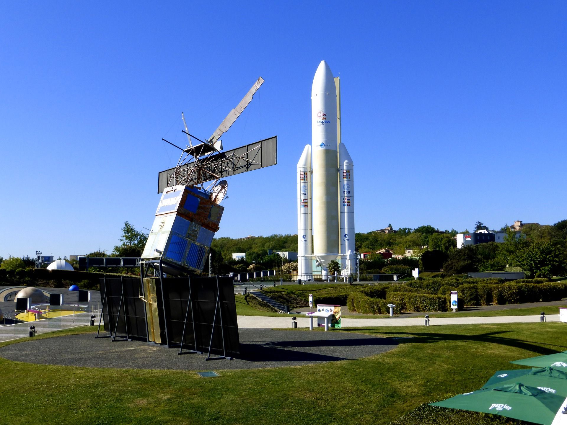 A rocket on a launch pad with a satellite and a crane in the foreground.