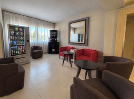 Habitación de hotel con zona de estar, máquina de café y máquina expendedora.