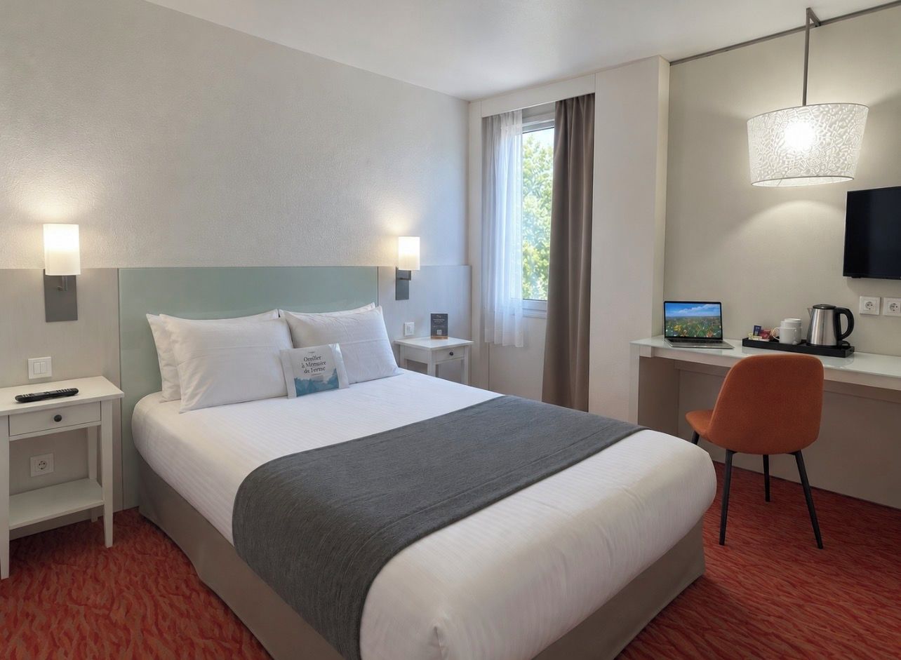 Habitación de hotel con cama, escritorio, silla, televisión y ventana con cortinas.