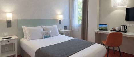 A hotel room with a bed, a desk, a chair, a TV, and a window with curtains.