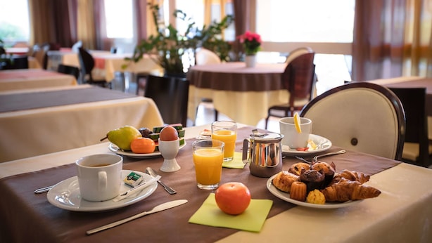 Een ontbijttafel gedekt met koffie, sap, gebak en fruit.