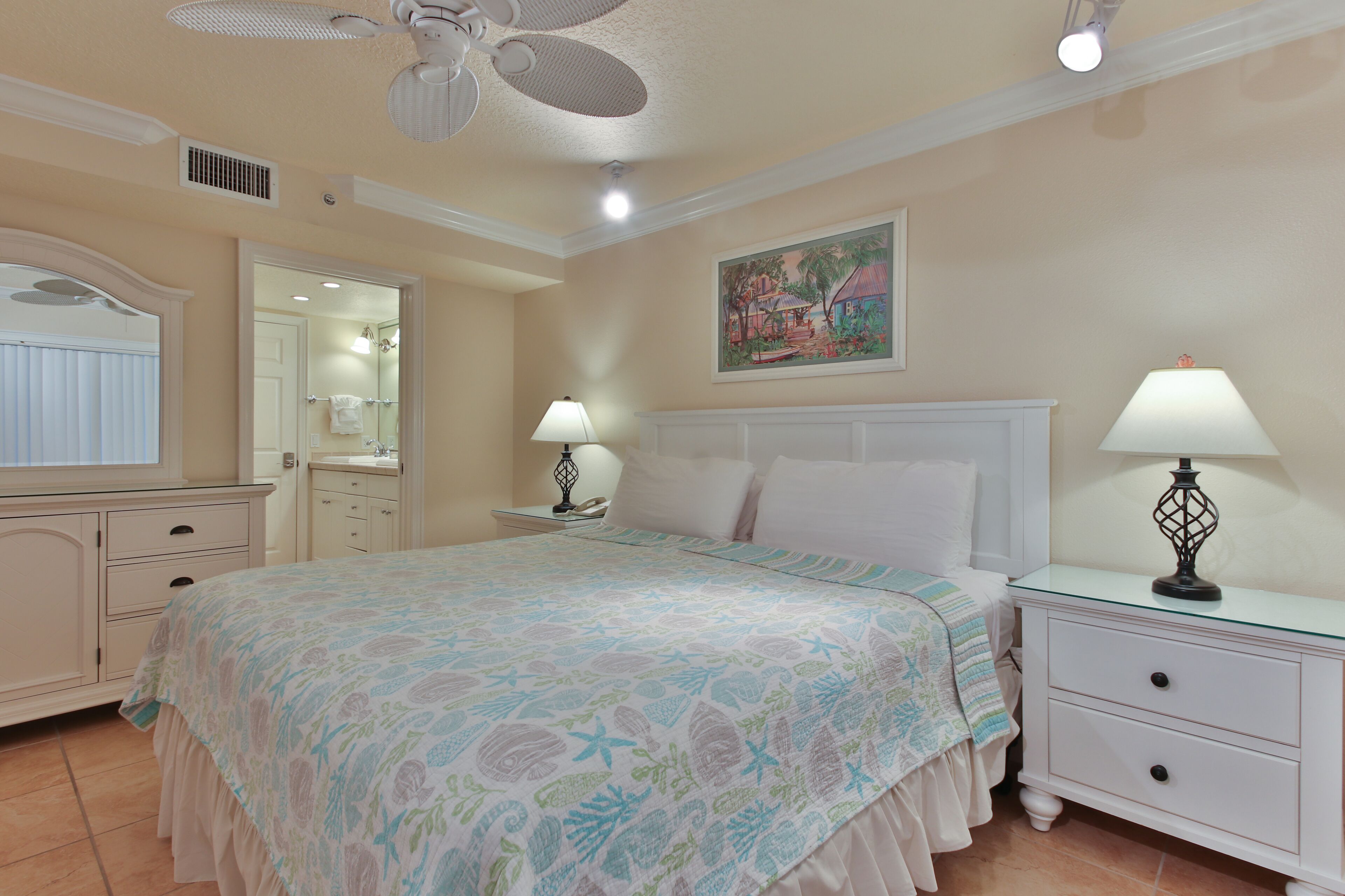 A bedroom with a bed, nightstands, a mirror, and a ceiling fan.