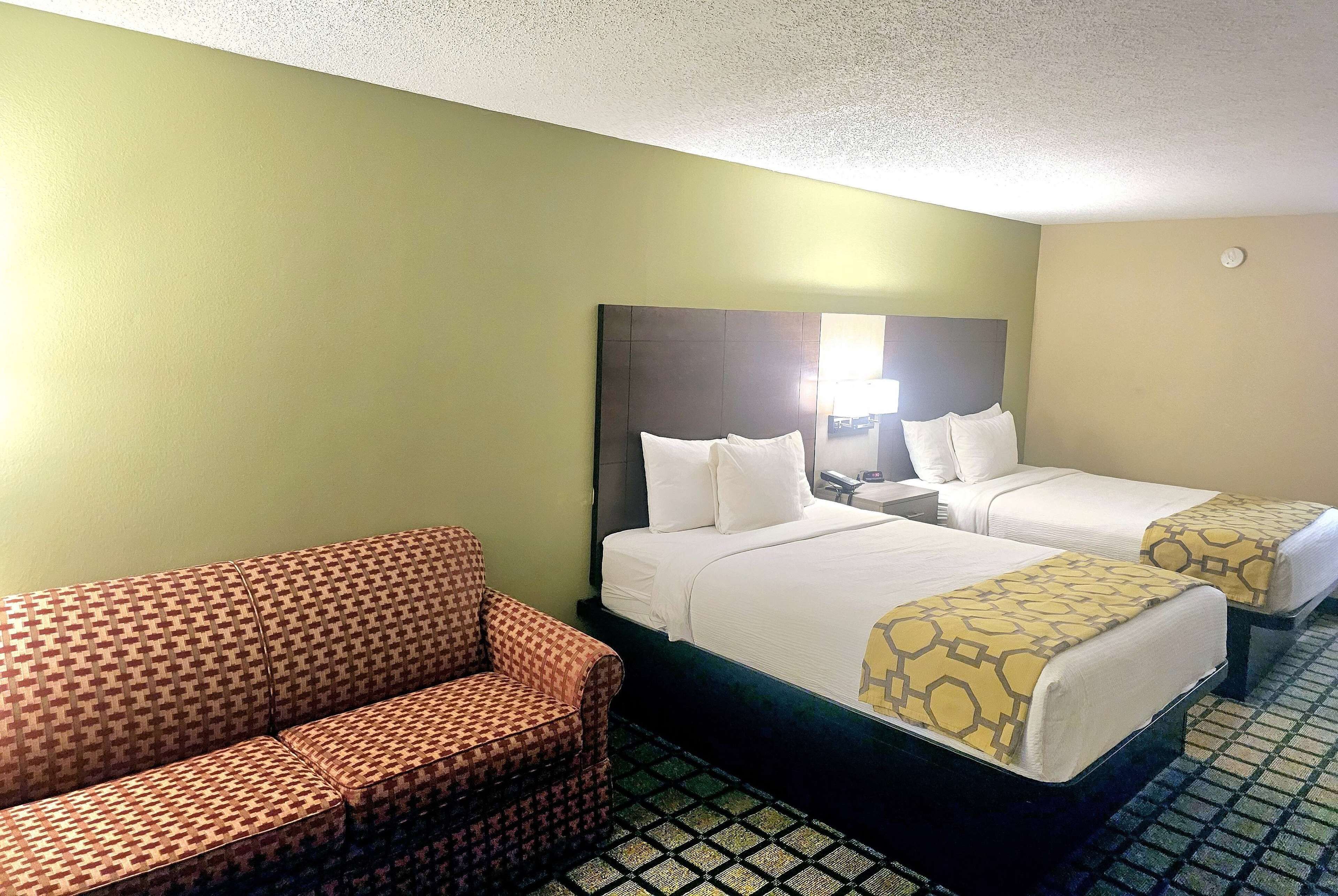 A hotel room with two beds, a sofa, and a patterned floor.