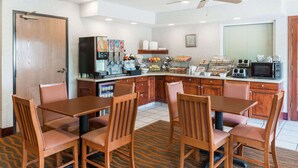 A compact kitchen with a dining area, equipped with a coffee machine, microwave, and various appliances. - Baymont by Wyndham Rolla (Rolla)