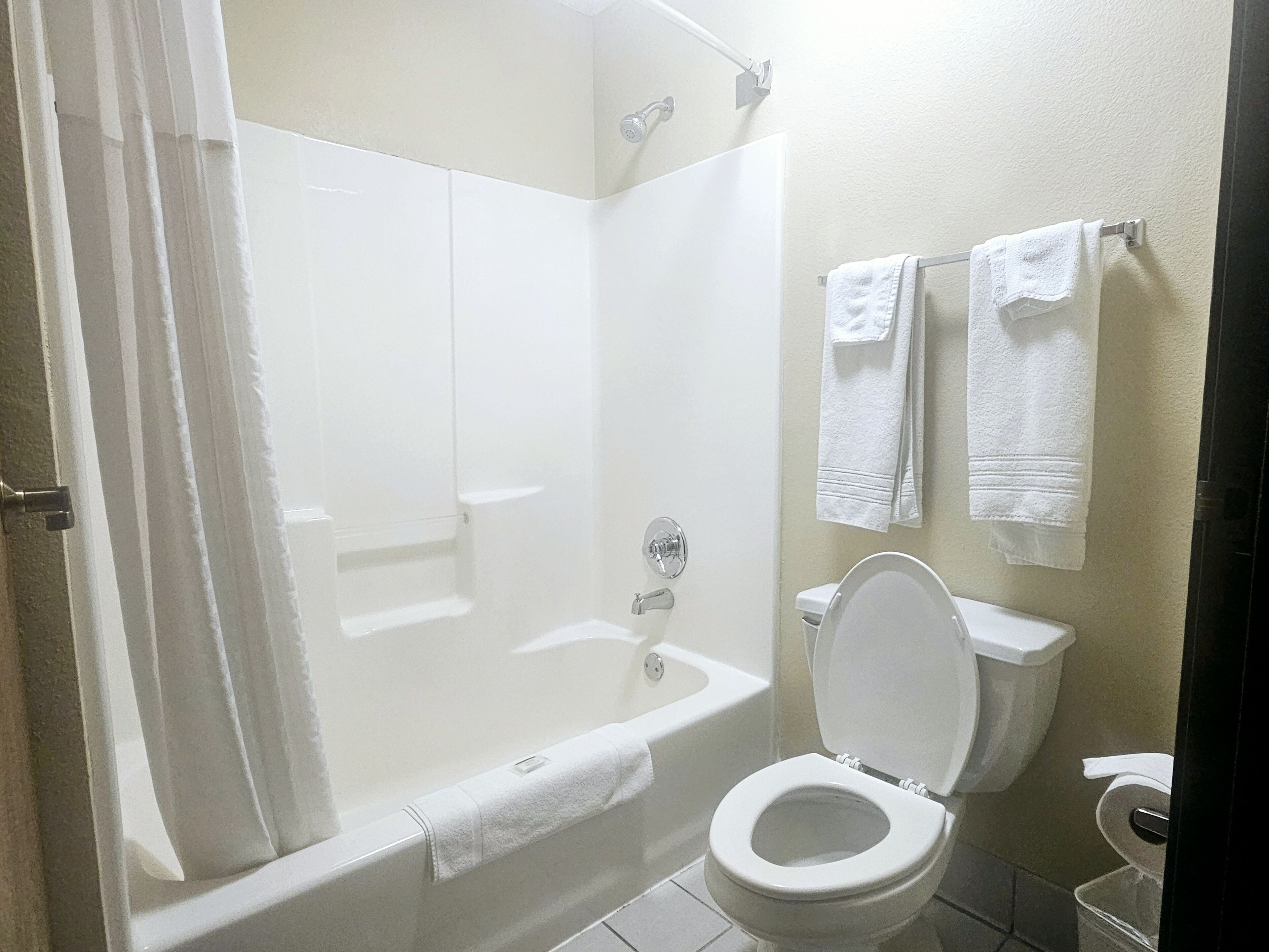 Un baño con bañera, inodoro y dos toallas colgadas en la pared.